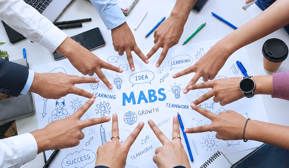 MABS students put their hands together over a sketch of ideas